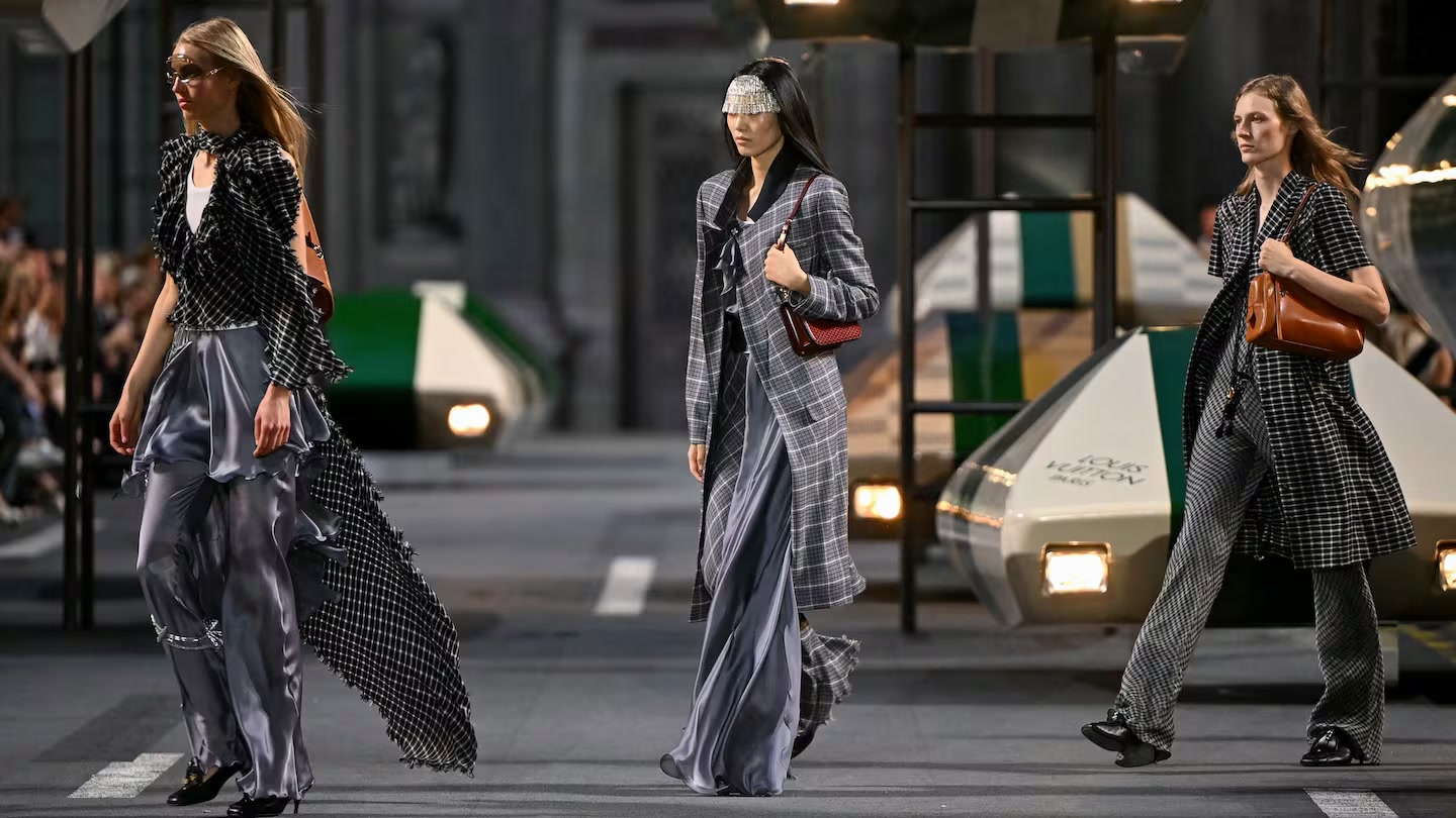 Three models in checked tailoring and satin walking a Louis Vuitton runway