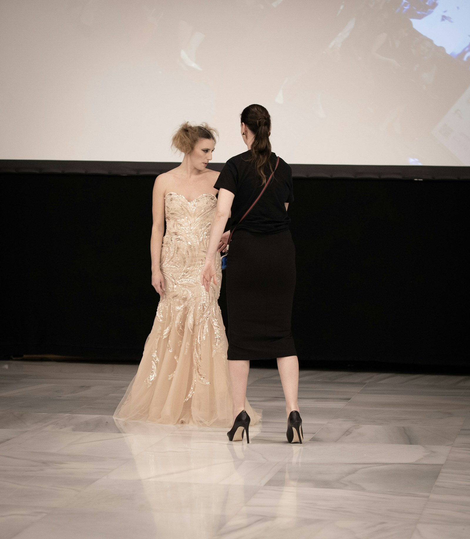 A model's outfit being adjusted backstage